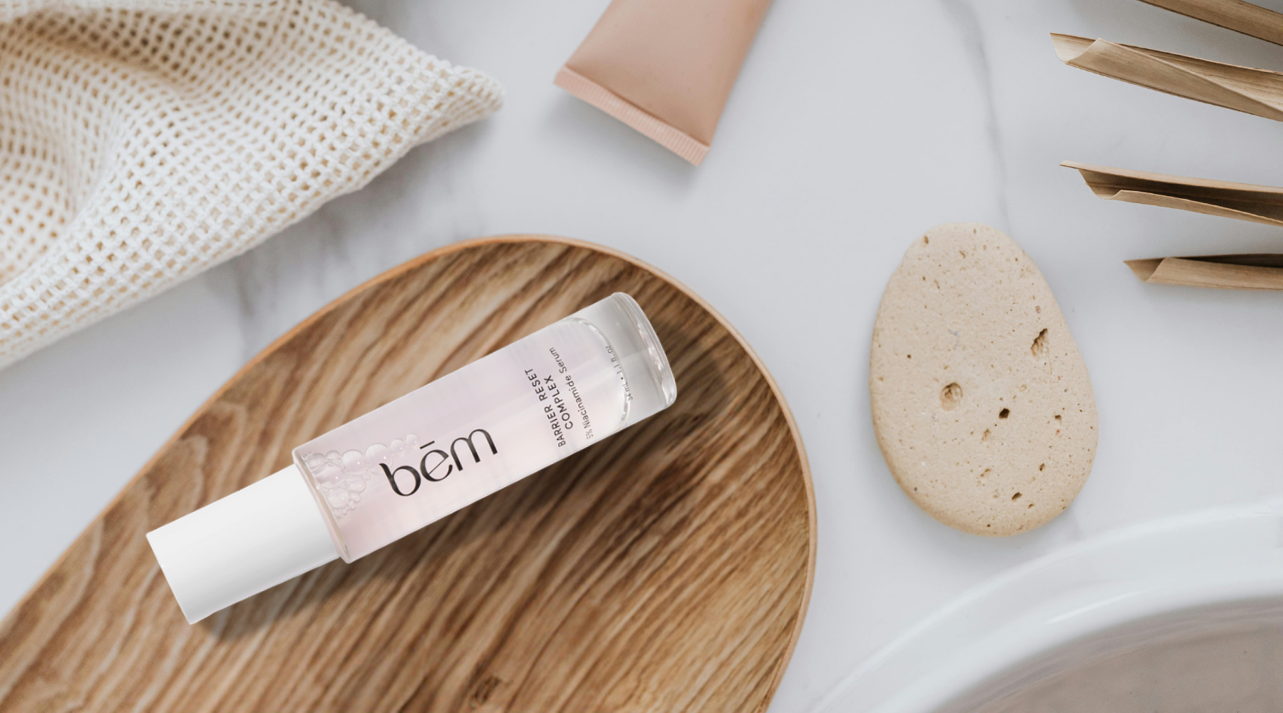 Serum bottle on wood tray on marble bathroom counter