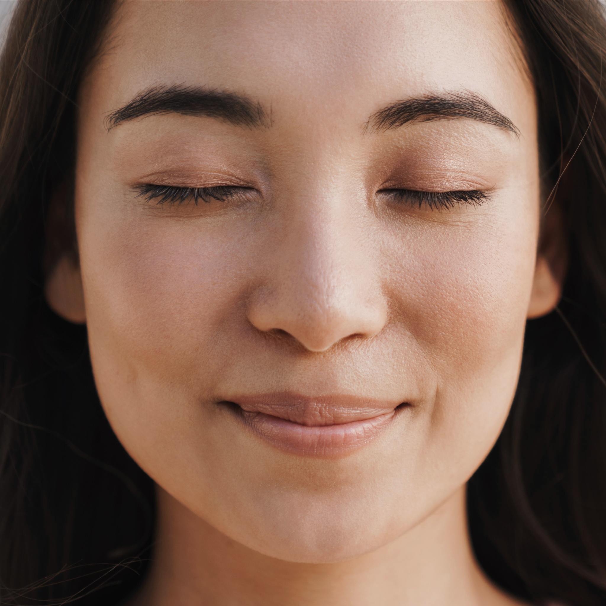 Close-up of a woman with closed eyes, showcasing her healthy skin.
