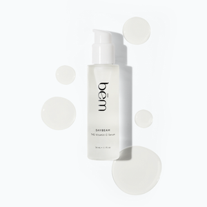 Bēm's Daybeam serum bottle with scattered droplets on a neutral background