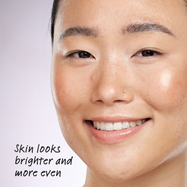 Close-up of a woman's face with text 'Skin looks brighter and more even' on a light background