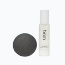 Daybeam serum bottle and a charcoal konjac sponge on a white background.