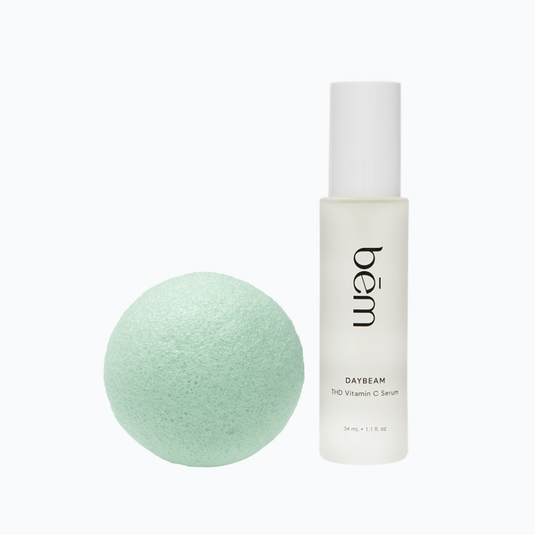 Daybeam serum bottle and a green tea konjac sponge on a white background.