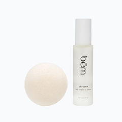 Bēm's Daybeam serum bottle and a round facial sponge on a neutral background