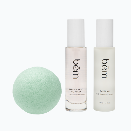 Two skincare bottles and a green tea konjac sponge on a white background.