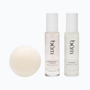 Two Bēm serum bottles and a round facial sponge on a neutral background