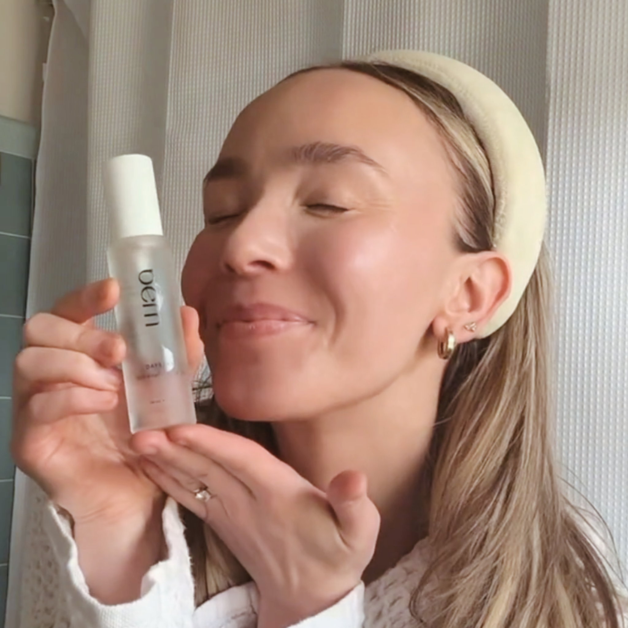 Woman holding Bēm's Daybeam serum bottle with a neutral background